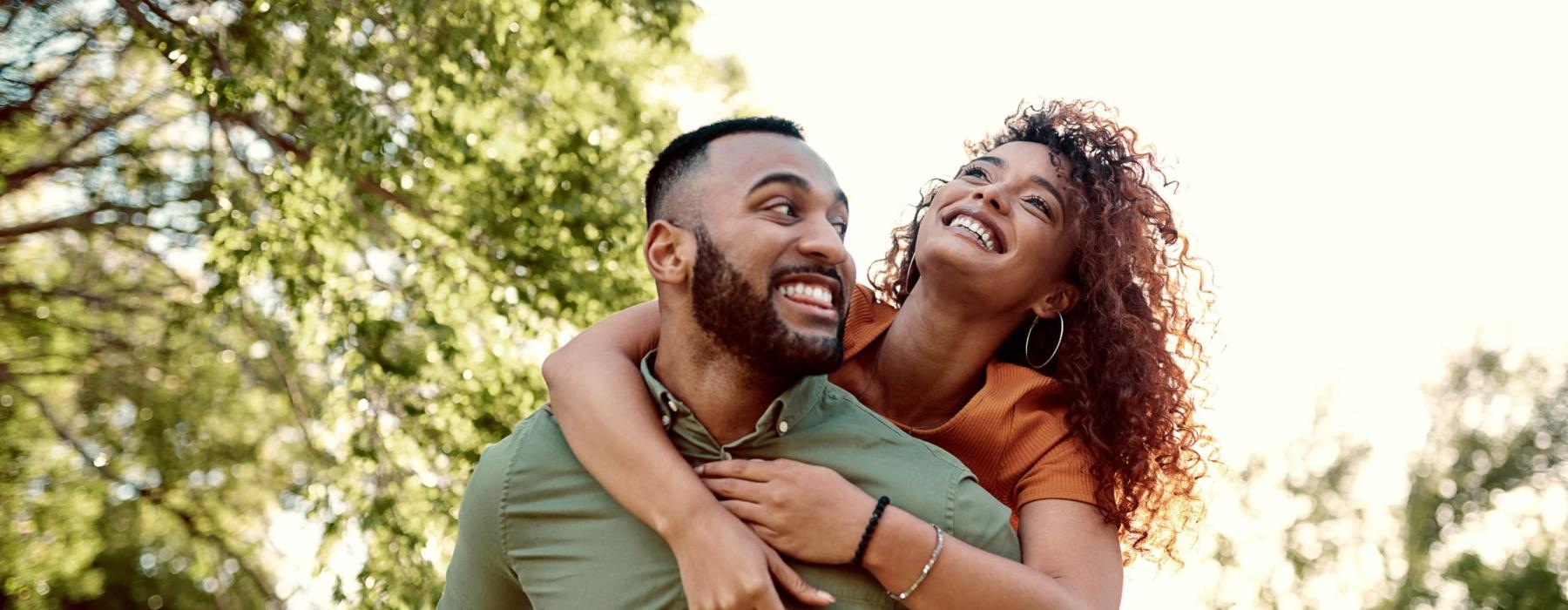 man piggybacks his wife in a park